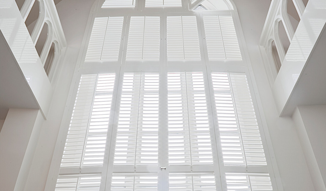 Witte shutters voor een hoog raam met een ronde vorm